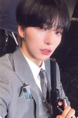 Photocard of Seoho wearing a grey suit and holding a pistol with a silencer