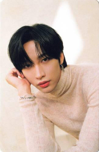 Photocard of Nine wearing a beige sweater and leaning on his hand, gazing into the camera