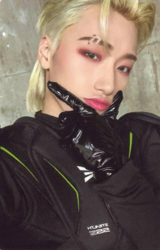 Photocard of San wearing black techwear and shiny black gloves holding a finger gun under his chin