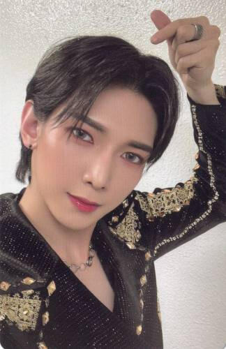 Photocard of Yeosang wearing a black and gold outfit and making a finger heart
