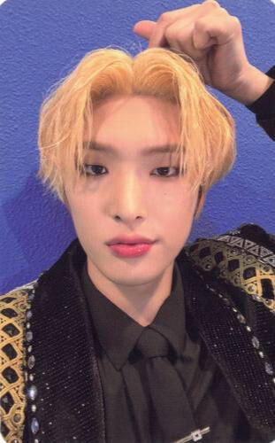 Photocard of Mingi wearing a black and gold outfit and making a finger heart