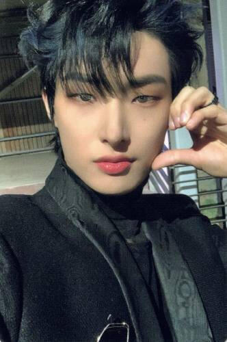 Photocard of Mingi wearing a black suit jacket and holding a hand heart to his cheek