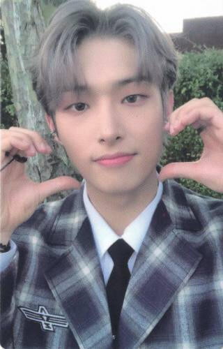 Photocard of Mingi wearing a grey flannel suit and holding two half hand hearts to his face