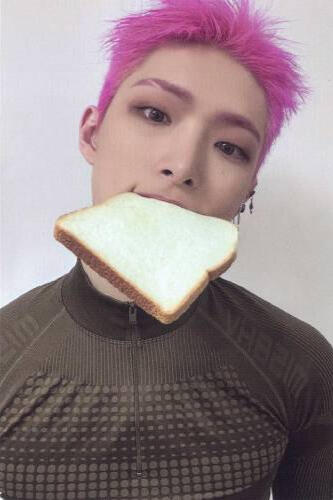 Photocard of Mingi wearing a green athletic shirt and holding a piece of bread in his mouth