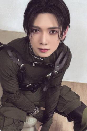 Photocard of Yeosang wearing dark green techwear and a black harness, looking up at the camera