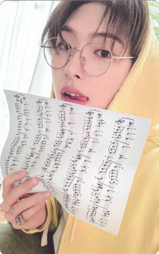 Photocard of Mingi sticking his tongue out and holding up sheet music