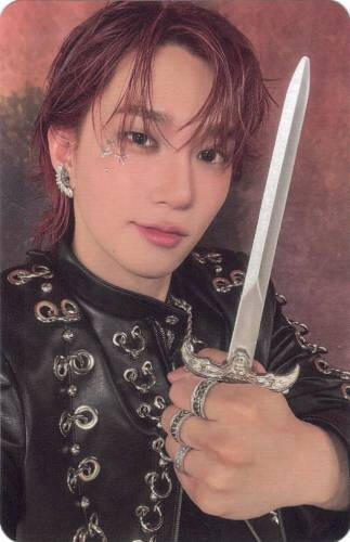 Photocard of Theo holding up a dagger with a smile