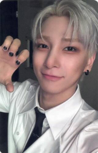 Photocard of Hangyul wearing a white shirt and black tie, making a clawed hand and smiling