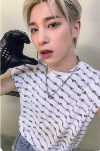 Photocard of Hangyul wearing a white tshirt and black motorcycle gloves, holding a hand heart to his cheek