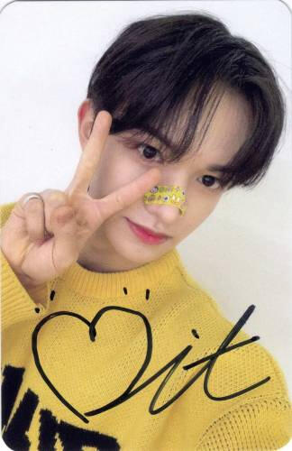 A signed photocard of Bit wearing a yellow sweater and making a peace sign