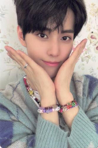 Photocard of Jinsik wearing a pale blue sweater and making a V with his hands under his face