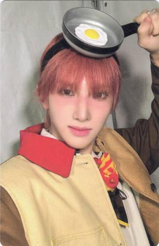 Photocard of Seeun holding a fake pan with a fried egg in it on his head