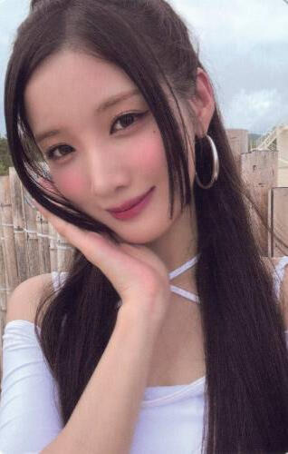 Photocard of Yuki wearing a low-cut white top and holding her face