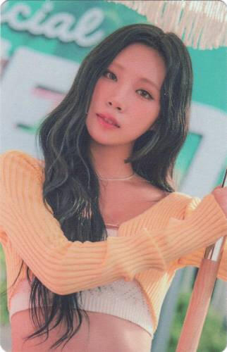 Photocard of Dosie wearing a white knit top and yellow cropped cardigan, gazing into the camera