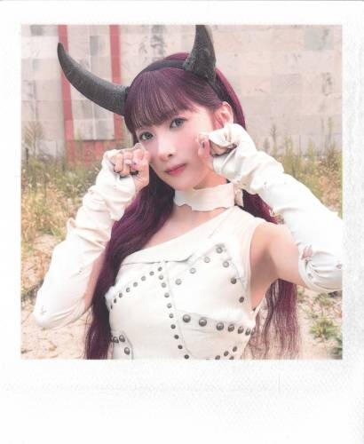 Fake polaroid of Yuki wearing a white outfit with devil horns