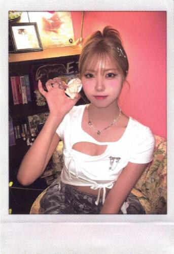 Polaroid of Ireh sitting in a chair holding a flower to her face