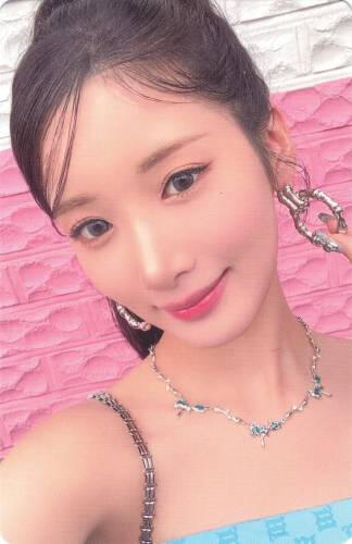 Photocard of Yuki wearing a blue dress and silver jewelry, holding her hoop earring and smiling