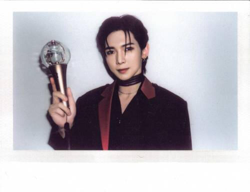 Polaroid of Yeosang holding up a lightstick