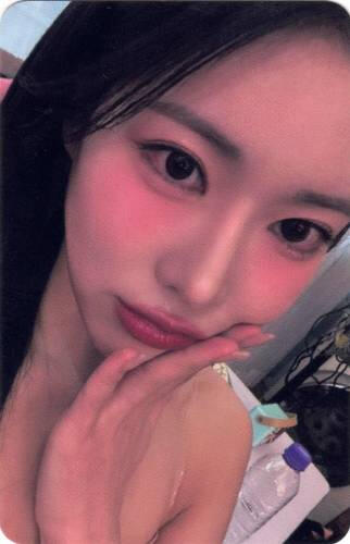 Photocard of Ayeon in pink light holding a hand to her cheek