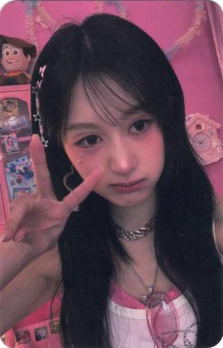 Photocard of Chaei making a peace sign in a pink room