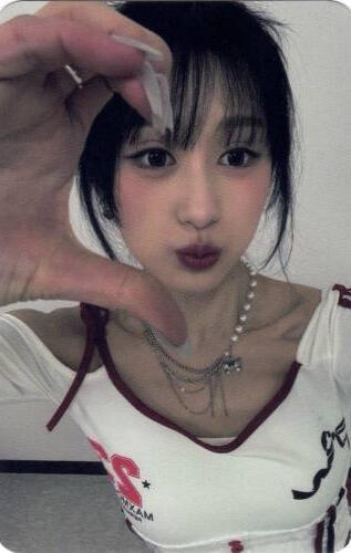 Photocard of Chaei holding up a half hand heart to the camera