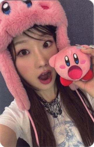Photocard of Yousom wearing a kirby hat and holding a small kirby plush, opening her mouth to match kirby