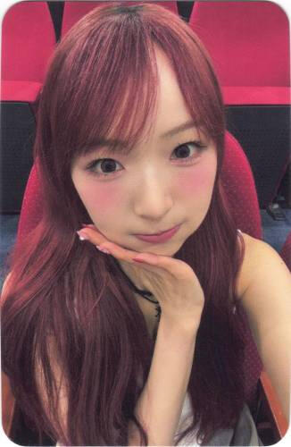 Photocard of Yume resting her face on her flat hand and puffing her cheeks slightly