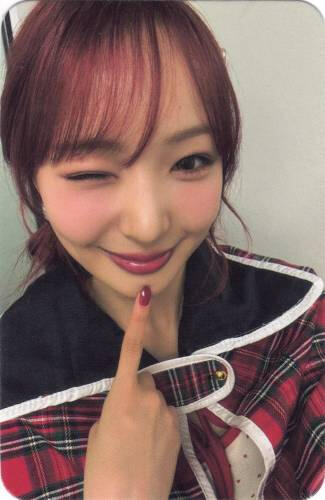 Photocard of Yume wearing a plaid cape and poking her chin with a wink