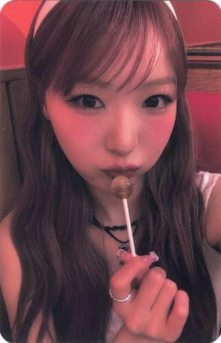 Photocard of Yume holding a lollipop to her lips