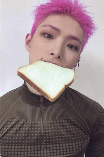 Photocard of Mingi wearing a green athletic shirt and holding a piece of bread in his mouth