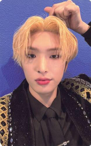 Photocard of Mingi wearing a black and gold outfit and making a finger heart