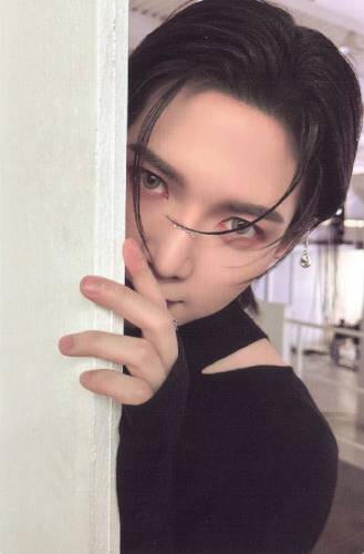 Photocard of Yeosang wearing a black sweater and peeking from behind a wall