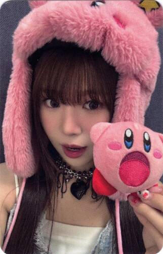 Photocard of Yuna wearing a kirby hat and holding a plush kirby by her open mouth