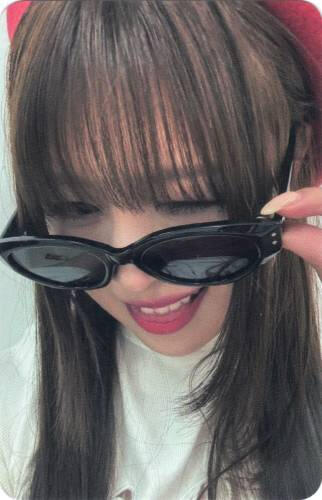 Photocard of Yuna holding her sunglasses and sticking her tongue out with a grin
