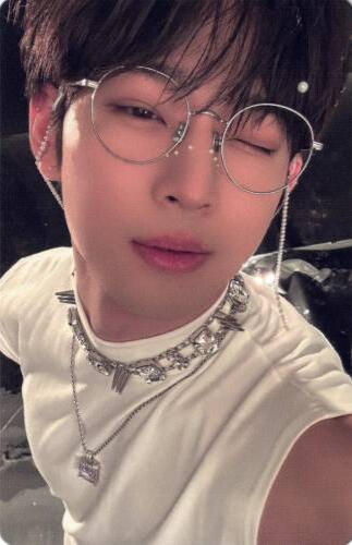 Photocard of Leedo wearing a white sleeveless shirt, silver jewelry, and thin silver glasses with a glasses chain and winking