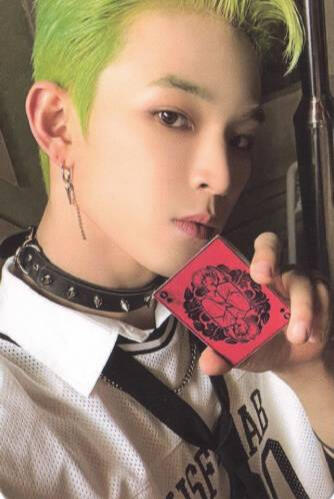 Photocard of Leedo wearing a white shirt, loose tie, and black spiked choker, holding up a red playing card