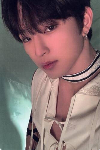 Photocard of Leedo wearing an open white shirt and white choker, looking into the camera