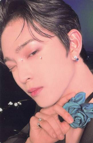 A photocard of a closeup of Leedo wearing black, holding a blue rose under his chin