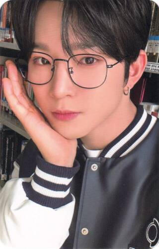 Photocard of Leedo wearing a letterman jacket and thin glasses, cupping his face