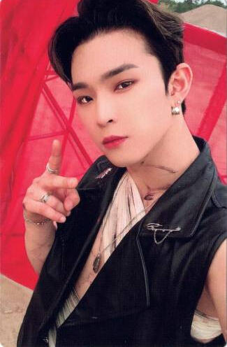 Photocard of Leedo wearing a black leather vest and bandages holding up a peace sign