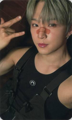 Photocard of Leedo in a black tank top and a tactical vest with a bandaid over his nose