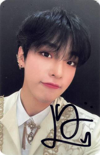 A signed photocard of Mujin in a white outfit with gold details