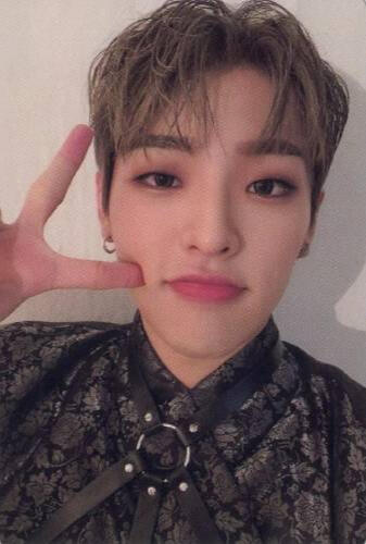 Photocard of Mujin wearing a black floral shirt and harness, holding up a peace sign