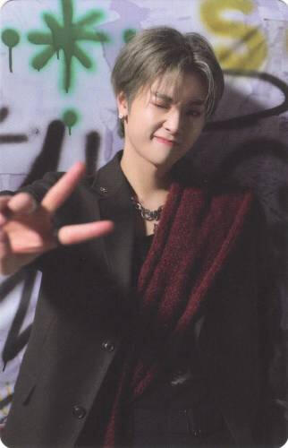 Photocard of Jungsu wearing a black and red suit, holding up a peace sign, and winking