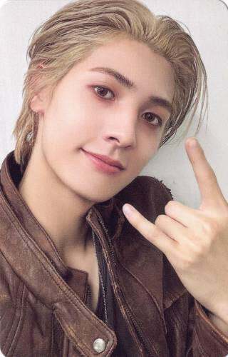 A photocard of Jooyeon wearing a brown leather jacket and making a "rock on" sign with his hand