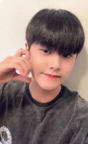 Photocard of Jahan wearing a black t-shirt making a half-heart with an animal ear with his hand against his cheek