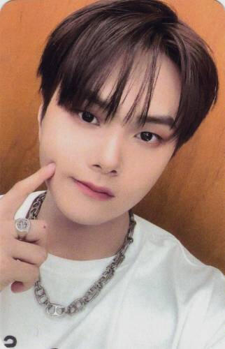 Photocard of Jahan wearing a white shirt and chain necklace while poking his cheek