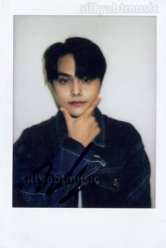 Signed polaroid of Jahan wearing a dark blue denim jacket and holding a finger gun under his chin