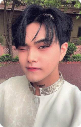 Photocard of Jahan wearing a white outfit with gold accents and winking