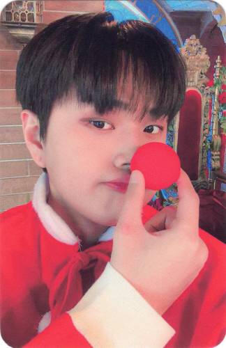 Photocard of Jahan wearing a red cape and holding a red clown nose to his nose